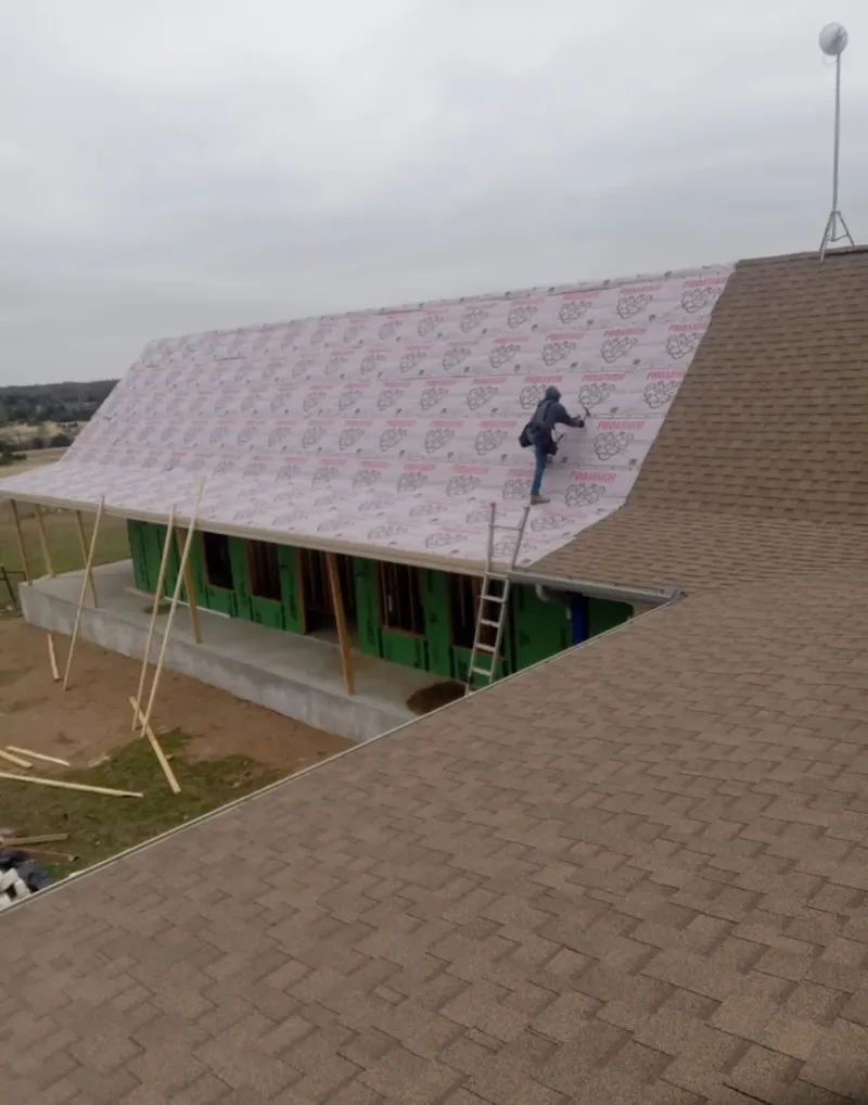 Worker preparing underlayment for a metal roof installation in Sequim